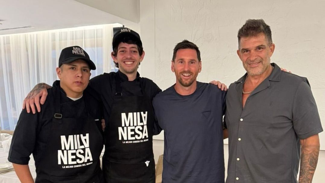 Lionel Messi posa junto a tres miembros del equipo de El Club de la Milanesa, con gorras y delantales negros de la marca