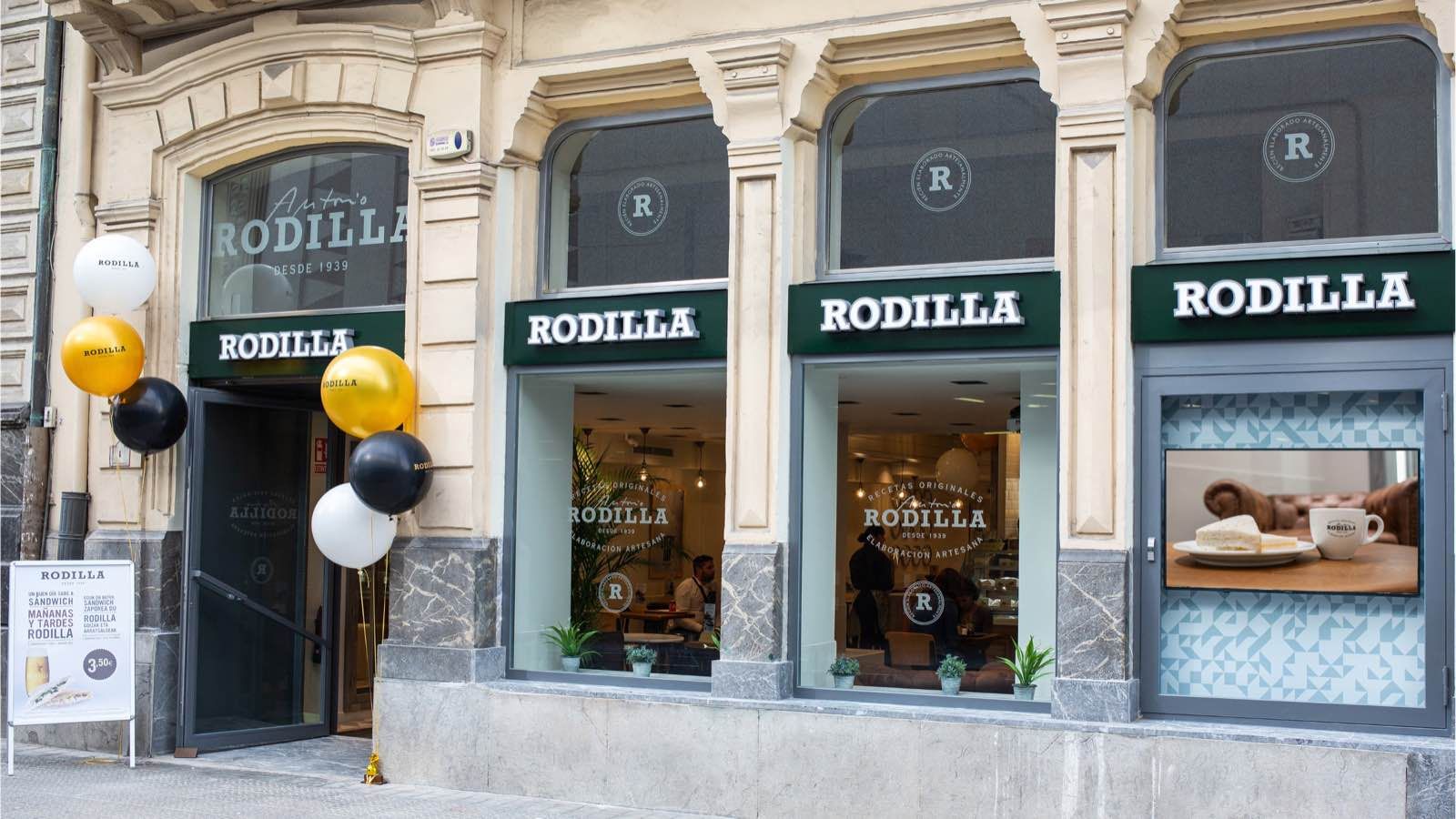 Fachada de una tienda Rodilla en día de inauguración, con globos en la puerta y un cartel de bienvenida en castellano y euskera