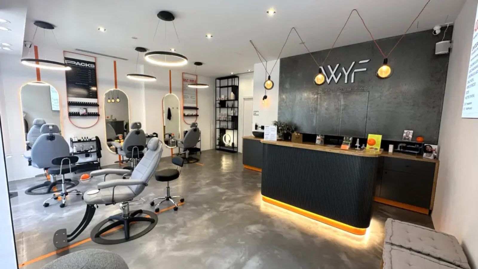 Interior del estudio de Work Your Face en Madrid, con sillones reclinables frente a espejos ovalados y el mostrador de recepción bajo el rótulo WYF